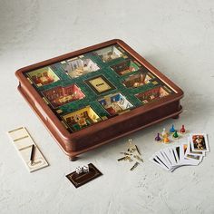 a wooden box filled with assorted items on top of a white table next to cards and magnets