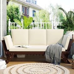 a white couch sitting on top of a wooden floor next to a potted plant