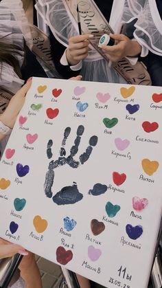 two people holding up a sign with handprints on it in front of them