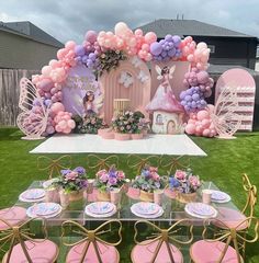 a table set up with pink and purple balloons for a princess birthday party in the backyard