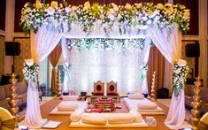 a decorated stage set up for a wedding ceremony with white and yellow flowers on it