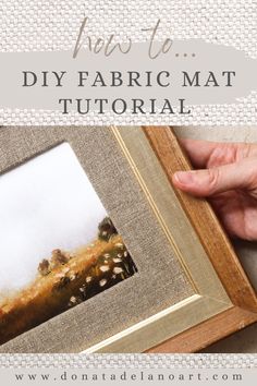 a hand holding a framed painting with the words how to diy fabric mat