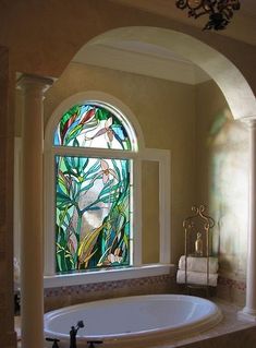 a bath tub sitting under a stained glass window