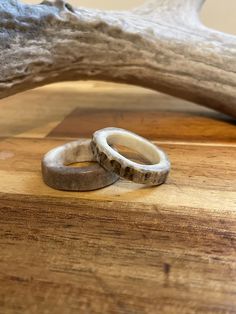 two wedding rings sitting on top of a wooden table next to antler's head