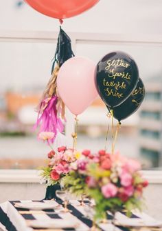 three balloons with writing on them sitting on a table next to flowers and other decorations