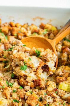 a casserole dish filled with stuffing and wooden spoons in it, ready to be eaten