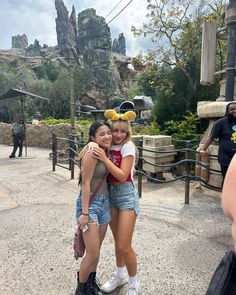 two young women hugging each other in front of mickey mouse ears at disneyland's animal kingdom