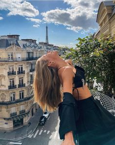 a woman standing on top of a roof looking at the sky with her hands behind her head