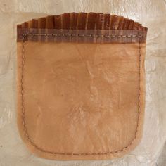 a piece of brown leather sitting on top of a white surface with stitching around the edges