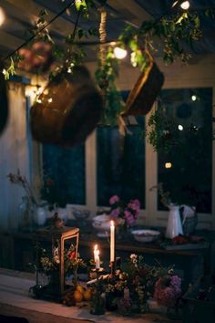 a table topped with flowers and potted plants next to a lit tea light candle