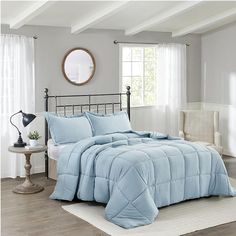 a bed with blue comforter and pillows in a bedroom next to a window,