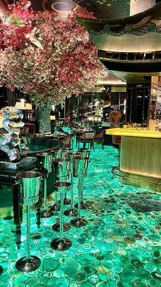 the interior of a fancy restaurant with green flooring and flowers on the bar area