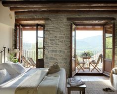 a bedroom with stone walls and doors leading to a balcony area that overlooks the mountains