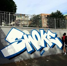 a man standing next to a wall with graffiti on it