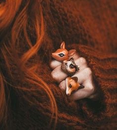 a close up of a person holding a fake baby deer in their lap with an acorn ring on it's finger