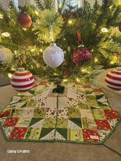 a quilted christmas tree skirt with ornaments hanging from it's sides on the floor