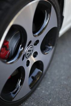 the tire of a white car with black spokes and red brake pads on it