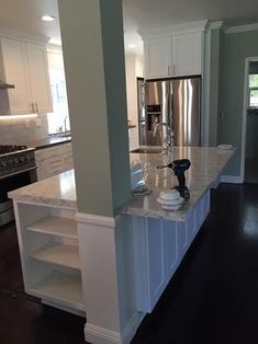 a kitchen with white cabinets and marble counter tops