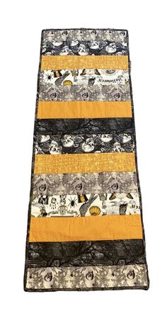 a yellow and black quilted table runner on top of a white surface with an orange stripe