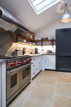 a kitchen with stainless steel appliances and skylight above the stove top oven, counter tops and cabinets