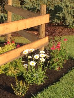 a wooden fence surrounded by flowers and grass