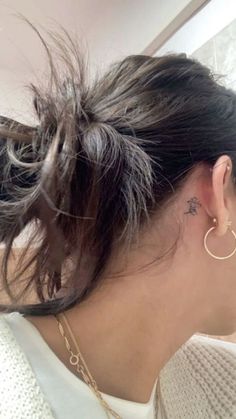 the back of a woman's head with a small tattoo on her left ear