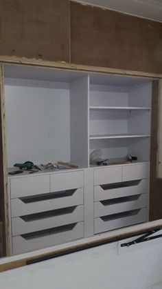 an unfinished room with white cabinets and drawers