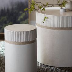 two white vases sitting next to each other on top of a carpeted floor