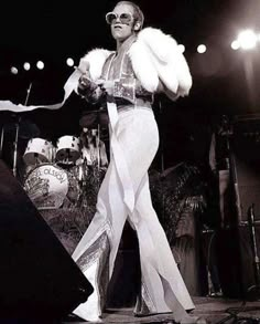 a woman in white is standing on stage with her legs spread out and she's wearing sunglasses