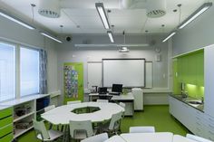 an office with white tables and green walls