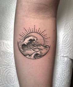 a black and white photo of a sun and wave tattoo on the left arm,