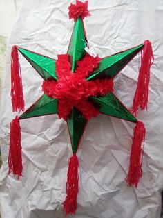 a green and red paper star with tassels on it