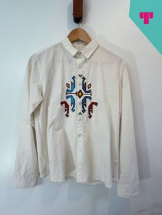 "This 1970s embroidered geometric button-up shirt from E+ is in great condition and very beautiful. The shirt is off-white cotton. The embroidered design may be South American, Indian, or Indigenous in style. The tag says XL but it fits more like a woman's MD or Men's X-Small. There are a couple of tiny spots but they are barely noticeable. I can send photos.  Women's MD / Men's XSmall Pit-to-Pit length 18\" Length 23\" Color off-white with multi-colored geometric embroidery.  Sold as is. Message for any questions." Embroidered Button Up Shirt, Indigenous Design, Geometric Embroidery, Women's Button Down Shirt, South American, American Indian, Embroidered Design, White Tshirt, Womens Clothing Tops