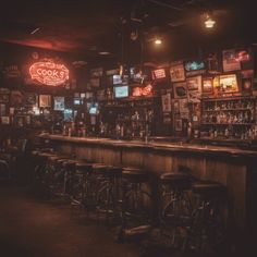 a dimly lit bar with stools in front of it and several television screens on the wall