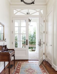 an entryway with a rug, mirror and door