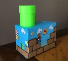 a cardboard box with a green cup on top of it sitting on a wooden table