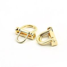 two pairs of gold colored metal clips on a white background with clippings in the middle