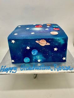 a birthday cake that is shaped like an outer space box with stars and planets on it