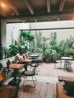 a person sitting at a table in a room with lots of plants on the walls