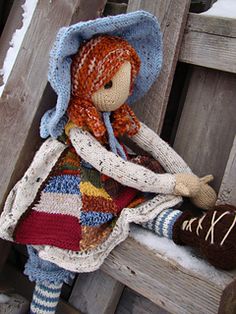 a doll sitting on top of a wooden bench with a blanket over it's head