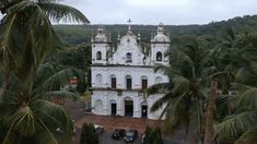 an old white church surrounded by palm trees