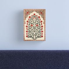 an intricately decorated wall hanging on the side of a bed