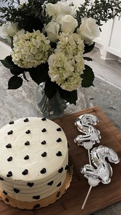 a white cake sitting on top of a wooden cutting board next to a vase filled with flowers