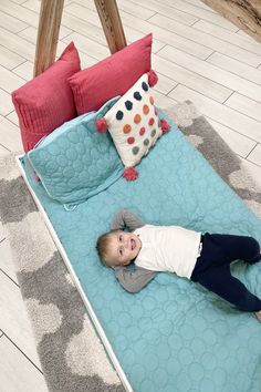 a little boy laying on top of a blue bed