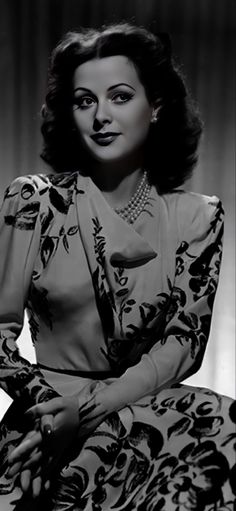 an old black and white photo of a woman wearing a dress with flowers on it