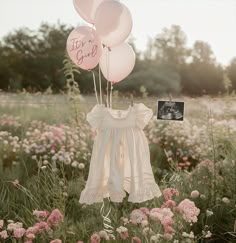 some pink balloons are in the grass with a baby's name on them and a photo frame