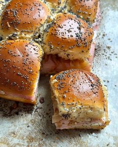 ham and cheese sliders on a sheet of parchment paper with poppy seed sprinkles