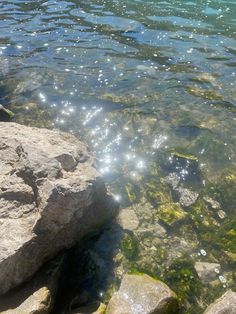 the water is crystal clear and there are rocks in the foreground with sun shining on them