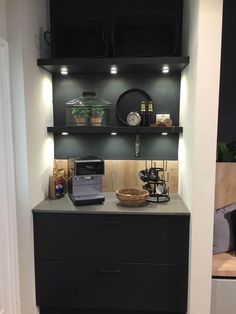 a kitchen with black cabinets and shelves filled with food on top of countertop next to an open door