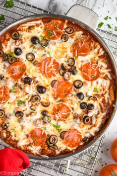 a pizza sitting on top of a pan covered in cheese and toppings next to tomatoes